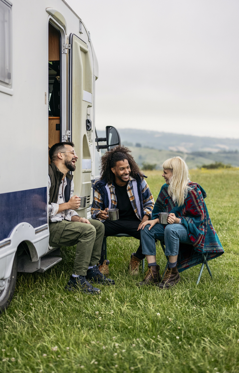 Group of Friends Relaxing by a Camper Van in Nature